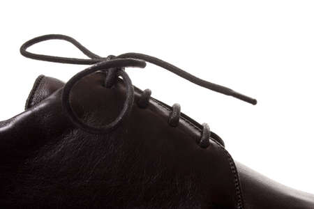 Fragment of classic black shoe with laces. Isolated on white backgroundの写真素材