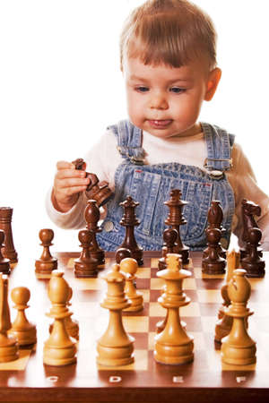  girl behind chess desk holding a chess piece in her hand. Isolated on white background.の写真素材