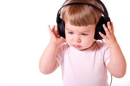 Little girl listening to music in the headphones. Studio shot, isolated on white background.の写真素材