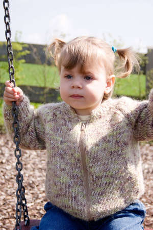 Portrait of little girl sitting on swing outdoors.の写真素材