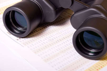 Binoculars on table with financial figuresの写真素材