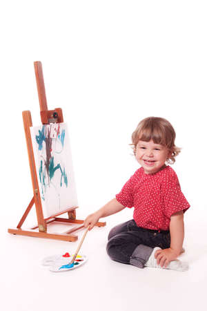 2 year old girl in profile, painting on an easel. Isolated on a white studio background.の写真素材