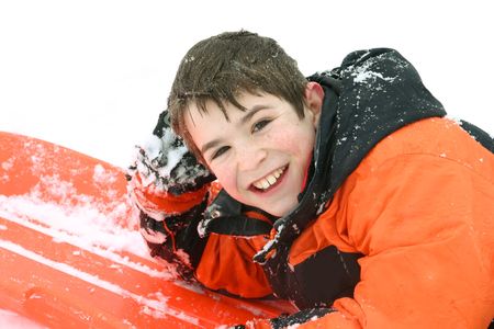 Boy Smiling Laying on his Sledの写真素材