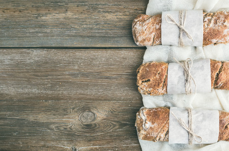 Freshly baked rustic  village bread (baguette) set on rough wood background with a copy space. Top...