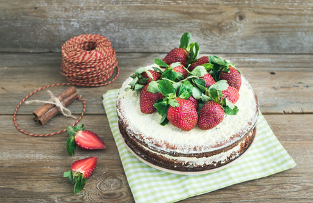 Rustic spicy ginger cake with cream-cheese filling and fresh strawberries with a rough wood...