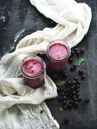 Fresh healthy smoothie in glass jars with blueberries and mint over dark grunge backgroundの写真素材