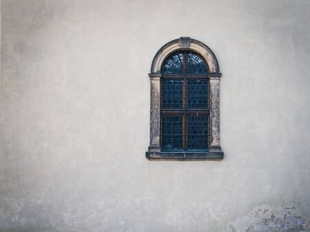 Antique medieval window with iron bars and old white shabby wallの写真素材