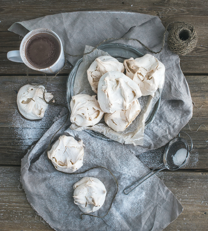 White meringue and mug of hot chocolate on a rustic wooden table. Black background, top viewの写真素材