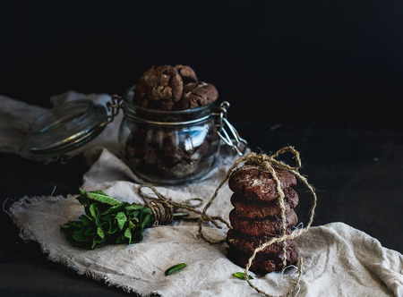 Dark chocolate chip cookies with fresh mint on dark background