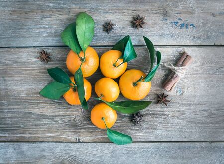 Fresh mandarines with cinnamon sticks and anise stars over a rough wood background. Top viewの写真素材