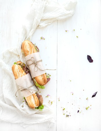 Sandwiches with beef, fresh vegetables and herbs over white wood backdrop, top view, copy spaceの写真素材