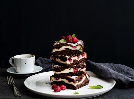 Brownies-cheesecake tower with raspberries on white ceramic plateの写真素材
