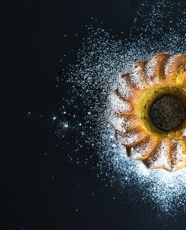 Moist orange bunt yogurt cake with sugar powder, dark grunge . Top view, copy space