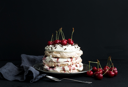 Pavlova cake with fresh cherry, cheese cream and chocolate chips in vintage silver plate over dark grunge backdropの写真素材