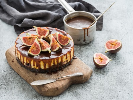 Cake with fresh figs and salted caramel on wooden serving board over grunge background, selective focusの写真素材