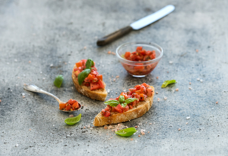 Tomato and basil bruschetta sandwich over grunge gray background, selective focusの写真素材
