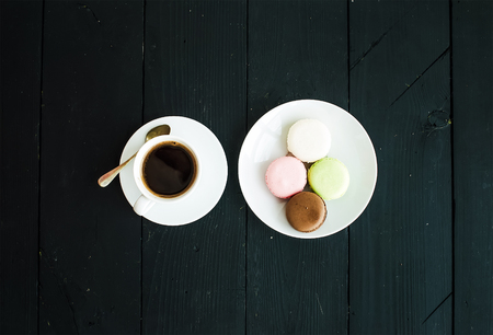 Macaron cookies, cup of espresso over black wooden backdrop . Top viewの写真素材