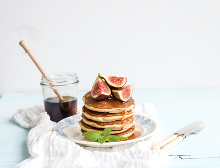 Pancake tower with fresh figs and honey on a rustic plate. White background, selective focusの写真素材