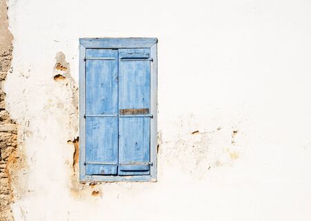 Mediterranean style window. Blue on yellow wall with closed shuttersの写真素材