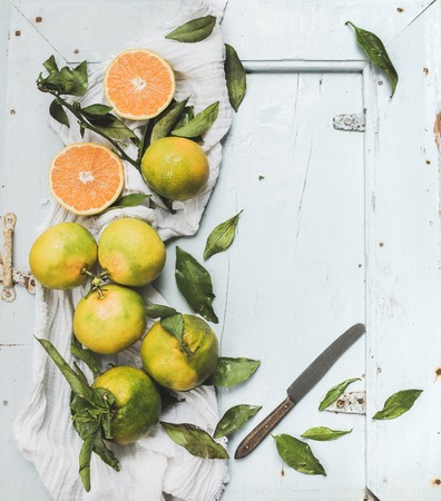 Fresh Turkish tangerines with leaves over blue rustic wooden backdrop, top view, copy spaceの写真素材