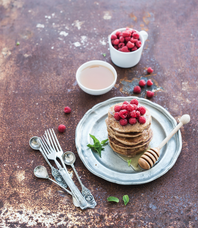 Breakfast set. Buckwheat pancakes with fresh raspberries, honey and mint leaves over grunge metal background, copy space, selective focusの写真素材
