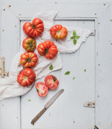 Fresh ripe hairloom tomatoes and basil on rustuc blue wooden surface, top view, copy spaceの写真素材