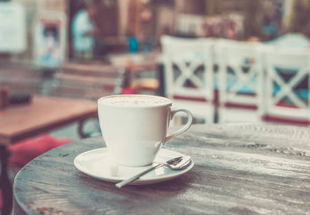 Cup of cappuccino on old dark wooden table in a street cafe, pastel gradingの写真素材