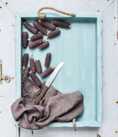 Small black corns on blue wooden tray over light rustic backdrop, top viewの写真素材