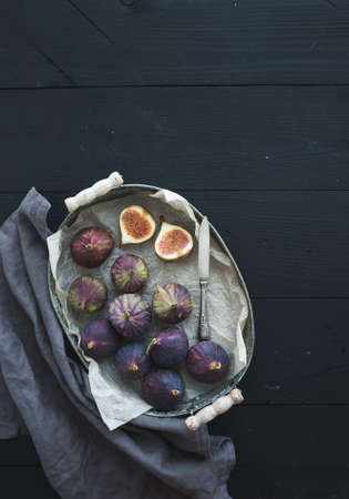 Vintage metal tray of fresh figs on dark background, top view, selective focus, top view, copy space