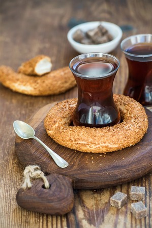 Turkish traditional black tea in a glass and turkish bagel simit on rustic  board over wooden...