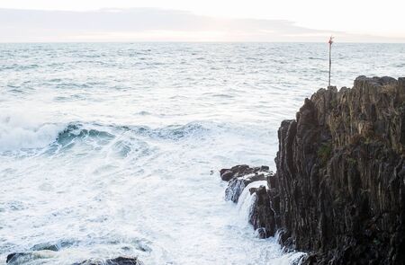 Waves breaking over cliff in Ligurian sea during a stormy winter day