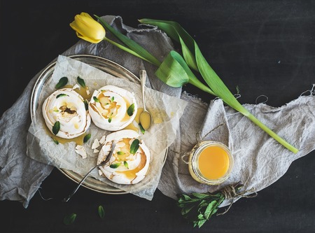 Merengues with lemon curd and fresh mint on silver tray, beige kitchen towel and grunge dark background, horizontalの写真素材