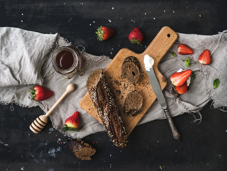 Breakfast set. Black baguette toasts with fresh strawberries, honey and mascarpone cheese on dark...