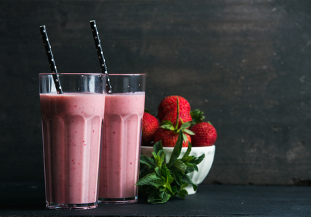 Strawberry and mint smoothie in tall glasses, bawl of fresh berries on dark rustic wood background. Selective focus, copy spaceの写真素材