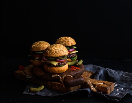 Fresh beef burgers with pickles and spices on rustic wooden boards, black background. Selective focus, copy spaceの写真素材