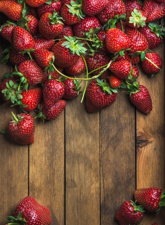 Summer fruit food frame. Strawberries over natural wooden background. Top view, copy space. Verticalの写真素材