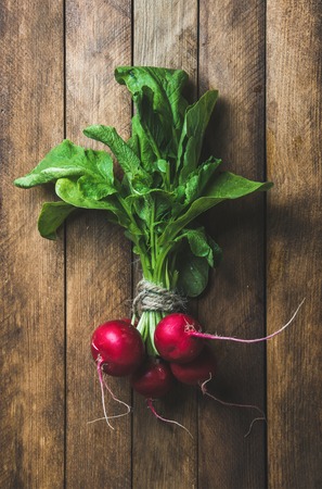 Fresh radish bunch over wooden background, top view, vertical compositionの写真素材