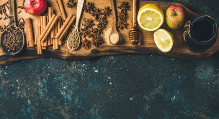 Ingredients for making mulled wine. Wine in glass bottle, honey, lemon, apples and spices on wooden board over old blue painted plywood background. Top view, copy space, horizontal compositionの写真素材