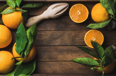 Fresh oranges with leaves in dark wooden tray over wooden background, top view, copy space, horizontal compositionの写真素材