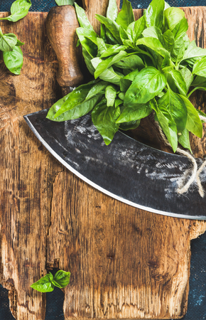 Fresh green basil and vintage herb chopper on rustic wooden bord, top view, copy space, vertical compositionの写真素材