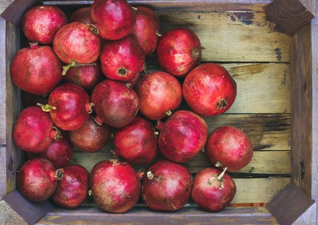 Turkish ripe red pomegranates in rustic wooden box, top view, copy space, horizontal compositionの写真素材