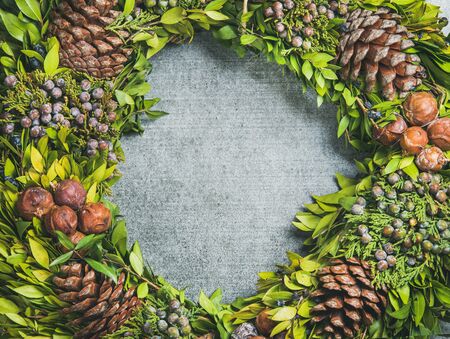 Christmas decorative green wreath with pine cones and herbs over grey concrete background, top view,...