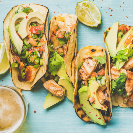 Healthy corn tortillas with grilled chicken, avocado, fresh salsa, limes and beer in glass over blue wooden background, top view, square crop. Gluten-free, allergy-friendly, weight loss conceptの写真素材