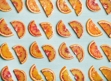Natural fruit pattern concept. Fresh juicy blood orange slices over light blue painted table background, top viewの写真素材