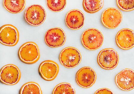 Natural fruit pattern concept. Fresh juicy blood orange slices over light marble table background, top viewの写真素材