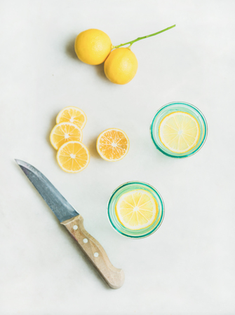 Morning detox lemon water in glasses and fresh lemons over light grey marble background, top view, vertical composition. Clean eating, weight loss, healthy, detox, dieting conceptの写真素材