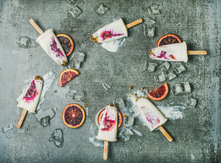 Healthy summer dessert. Blood orange, yogurt and granola ice cream on ice cubes over grey concrete background, top view, copy space. Clean eating, dieting, weight loss conceptの写真素材