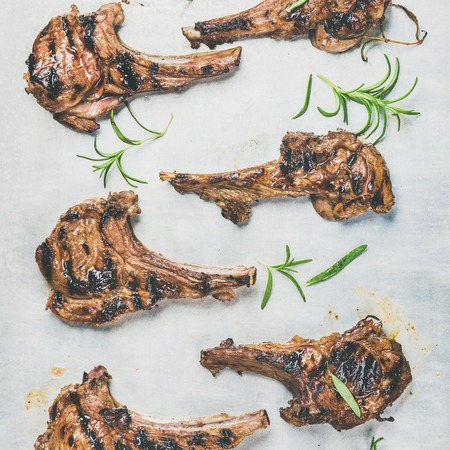Grilled lamb ribs with fresh rosemary over metal baking tray background, top view, square crop. Meat barbecue and slow food conceptの写真素材