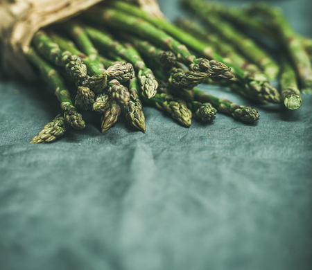 Fresh green asparagus over dark grey linen table cloth background, copy spaceの写真素材