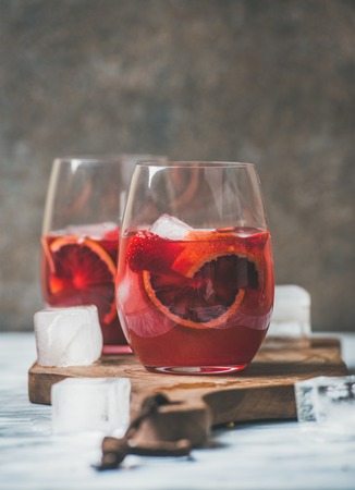 Blood orange and strawberry summer Sangria. Fruit refreshing rose wine cocktails in glasses with ice, dark background, copy spaceの写真素材